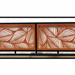 Dwa panele dekoracyjne z wycinanym laserowo wzorem liści, pomalowane na rdzawy kolor i oprawione w czarne ramy, tworzące element balustrady.