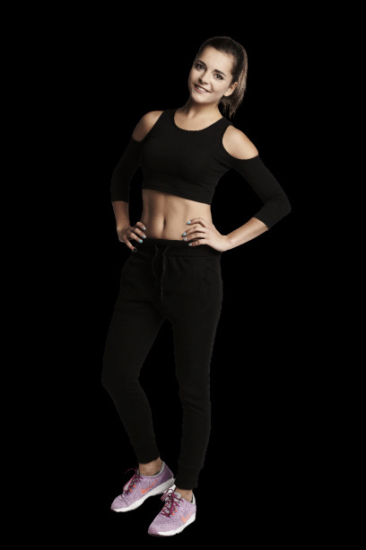 Uśmiechnięta, wysportowana młoda kobieta w czarnym sportowym stroju, z rękami na biodrach, prezentuje wyrzeźbiony brzuch na czarnym tle.