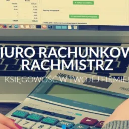 Kalkulator w dłoniach nad klawiaturą laptopa z otwartym arkuszem kalkulacyjnym na drewnianym biurku.