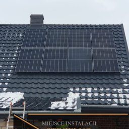 Mateusz Strzelecki - VIP Energy - Panel słoneczny o mocy 5,46 kWp zainstalowany na ciemnoszarym dachu pokrytym śniegiem, widoczna drabina oparta o ceglany budynek, miejscowość Strzelno, województwo kujawsko-pomorskie, logo firmy...