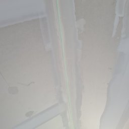 KHS System - Sufit po szpachlowaniu, widoczne ślady po łatach i zielona linia lasera wyznaczająca poziom.