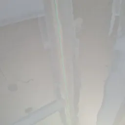 Sufit po szpachlowaniu, widoczne ślady po łatach i zielona linia lasera wyznaczająca poziom.