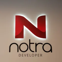 Podświetlane logo 'Notra Developer' z czerwoną literą 'N' na białej ścianie, widoczne elementy sufitu kasetonowego.