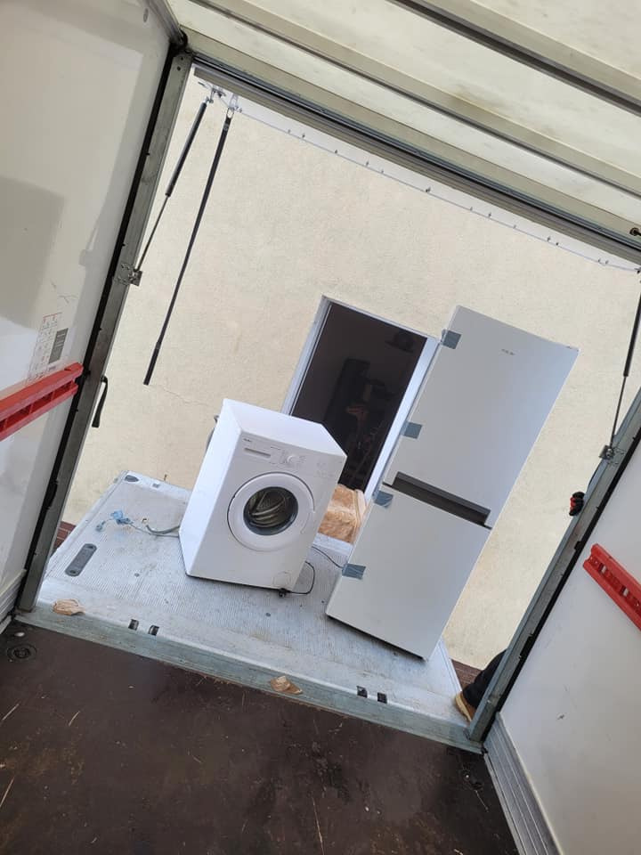 Pralka i lodówka zabezpieczone taśmą w przestrzeni ładunkowej pojazdu dostawczego, widok z góry.