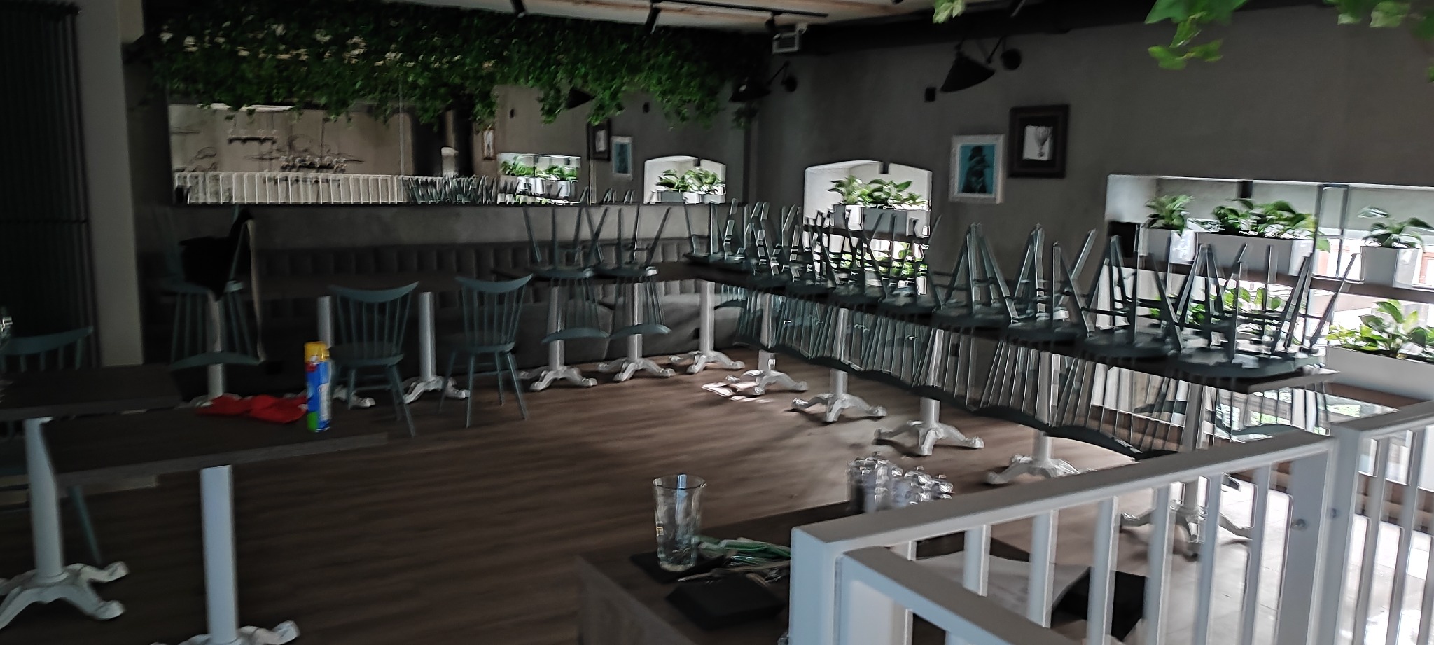 Wnętrze lokalu gastronomicznego z krzesłami odwróconymi na stołach, przygotowywanego do sprzątania lub po remoncie, widoczne środki czystości i akcesoria.