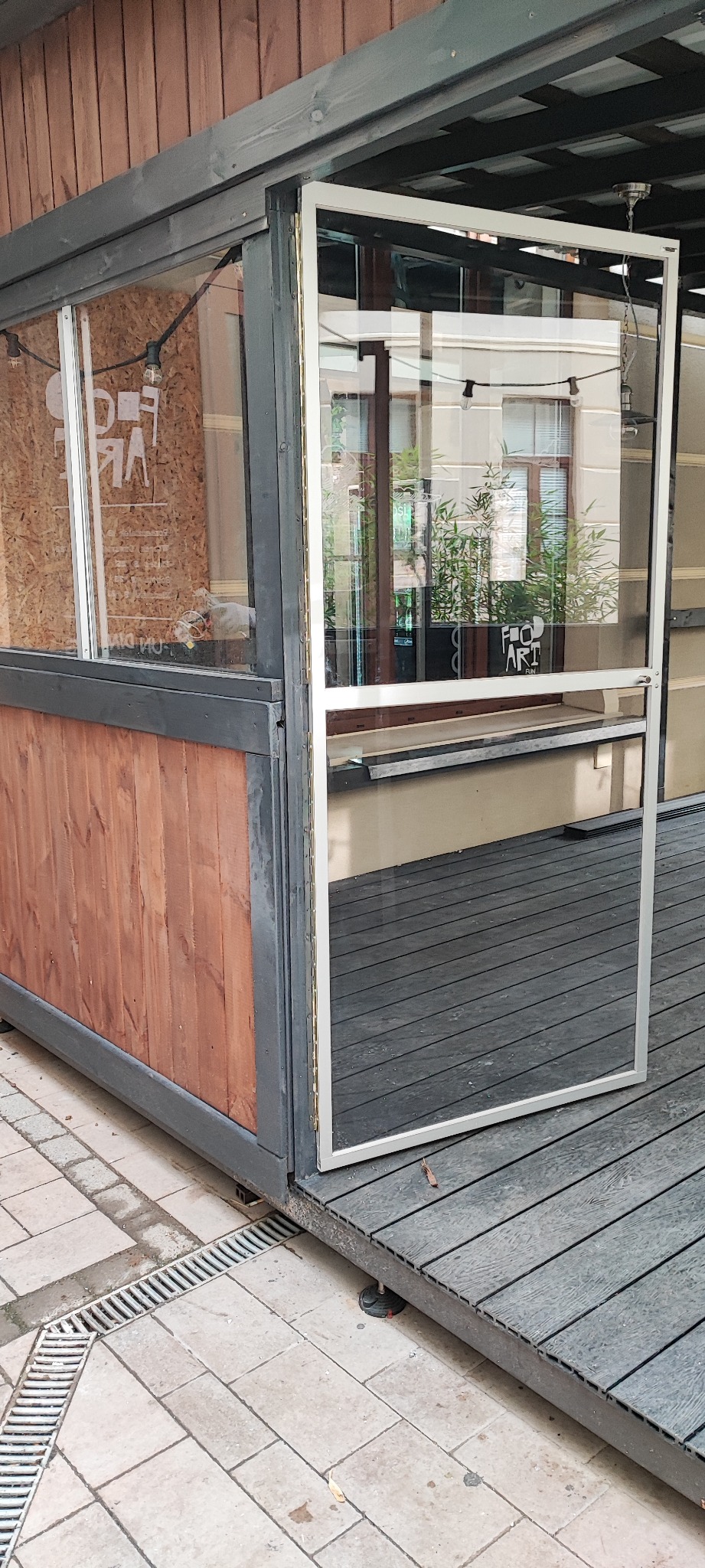 Montaż szklanej ściany z drewnianym obramowaniem w zewnętrznej konstrukcji z drewnianą podłogą.