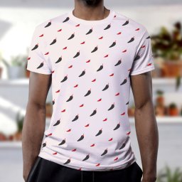 Rebound Studio - Mężczyzna w białej koszulce z powtarzającym się wzorem czarnych i czerwonych papryczek chili, na rozmytym tle regału z roślinami doniczkowymi.