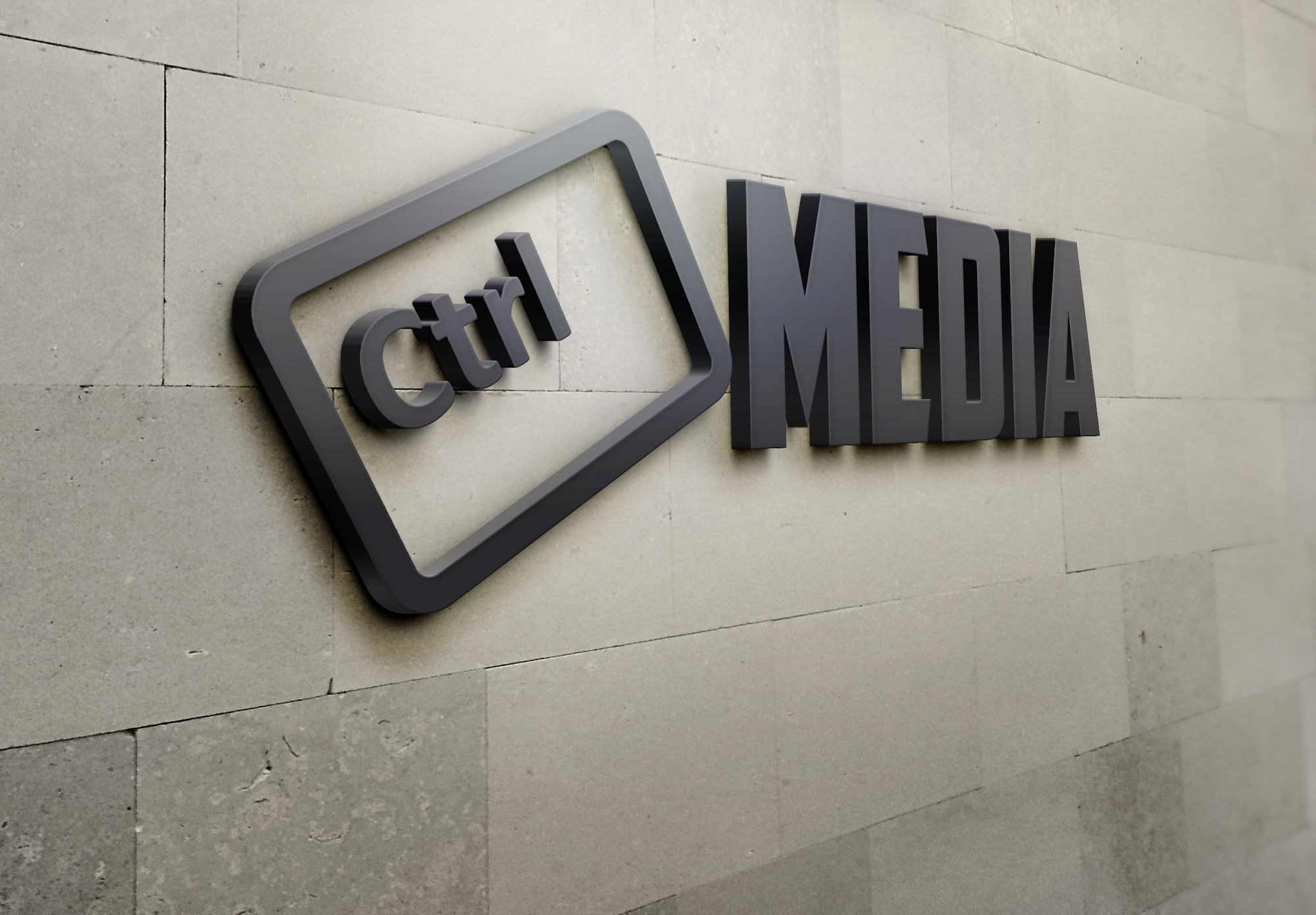Matowe, grafitowe litery 'MEDIA' i stylizowany symbol klawisza 'Ctrl' umieszczone na szarej, kamiennej ścianie z widocznymi spoinami.