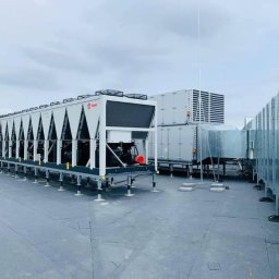 Palmil Sp. z o.o. - Rozległy system klimatyzacji przemysłowej z wieloma jednostkami zewnętrznymi na płaskim dachu, widoczne kanały wentylacyjne i anteny.