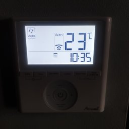 KLIMSPEC Przemysław Stróżewski - Biały panel sterowania klimatyzacją marki Airwell, zamontowany na szarej ścianie, wyświetlający temperaturę 23 stopnie Celsjusza i godzinę 10:35.