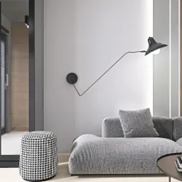 Minimalistyczny salon z szarą sofą modułową, pufą w pepitkę, lampą ścienną i stolikiem kawowym z książkami, widok na okno balkonowe.