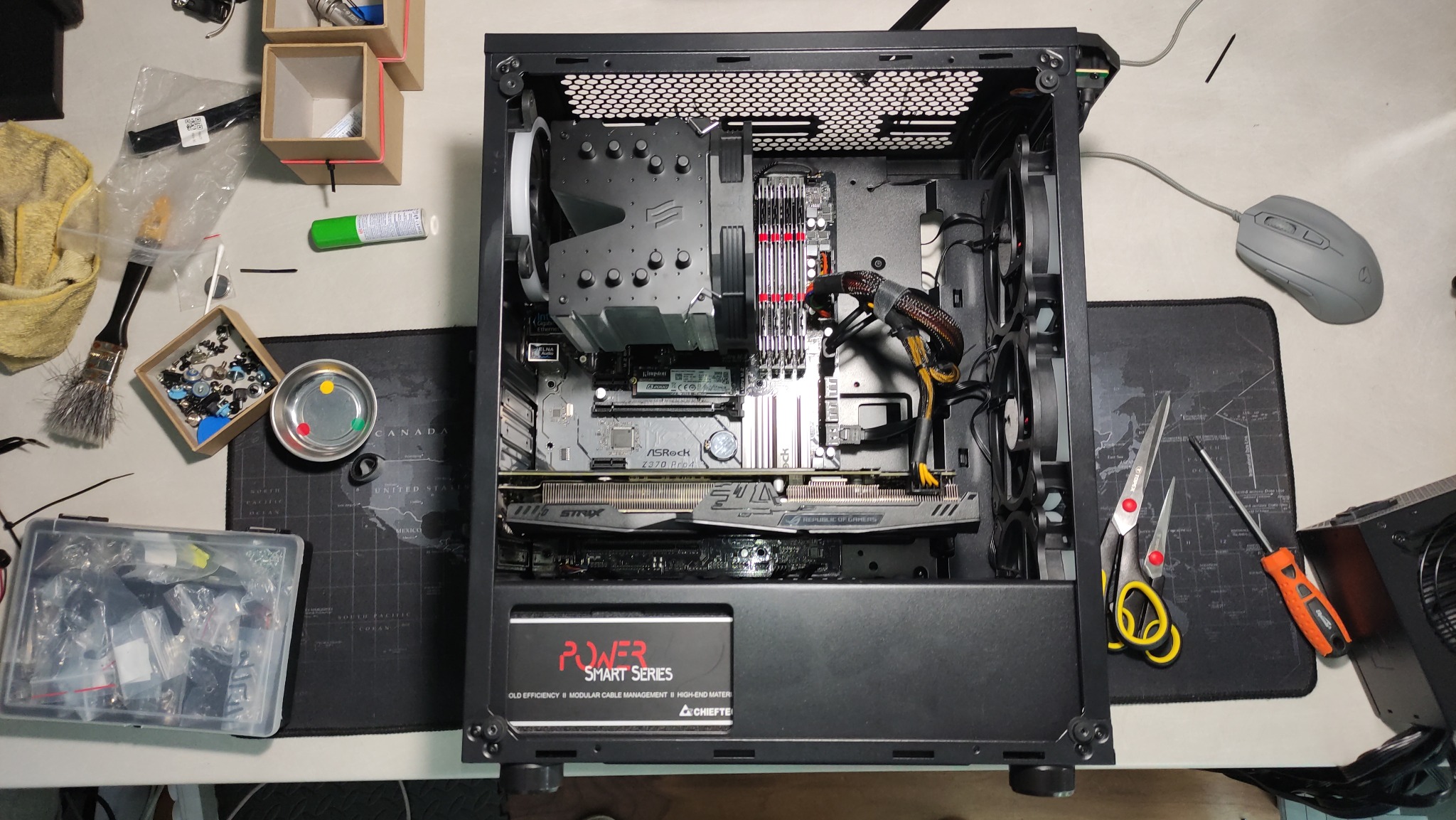 Wnętrze otwartej obudowy komputera stacjonarnego w trakcie montażu, widoczne komponenty: płyta główna ASRock Z370 Pro4, karta graficzna STRIX, chłodzenie procesora, pamięć RAM, zasilacz Chieftec...