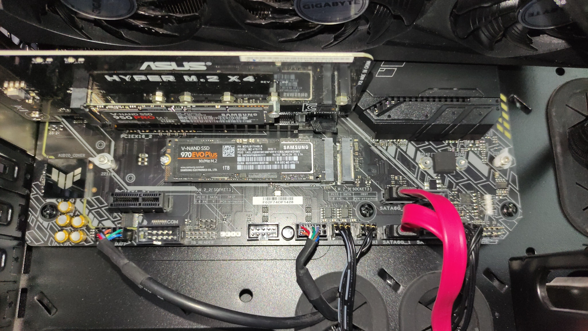 Wnętrze komputera stacjonarnego z zainstalowaną płytą główną ASUS, dyskami SSD Samsung 950 PRO i 970 EVO Plus oraz widocznymi kablami zasilającymi i wentylatorami chłodzącymi.