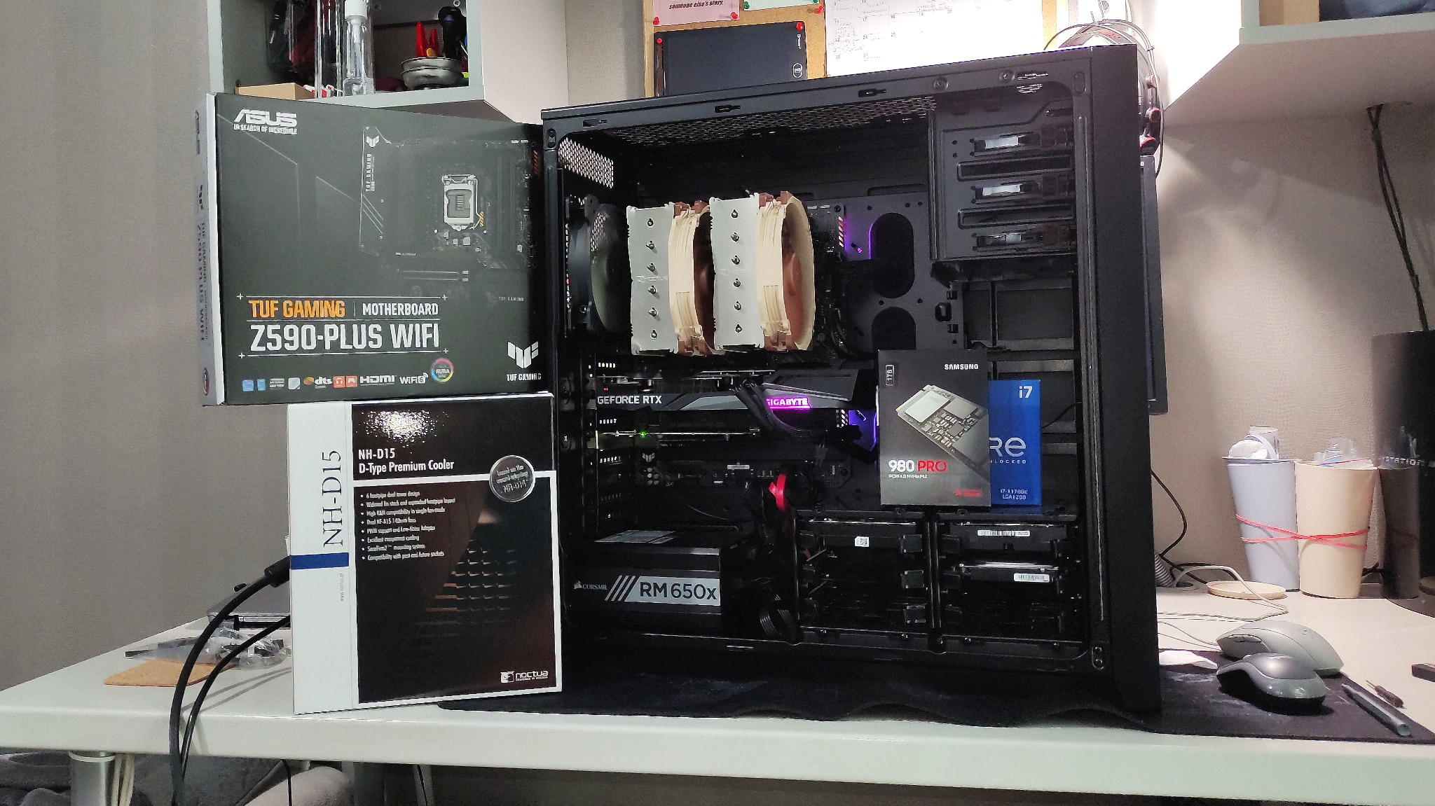 Wnętrze czarnej obudowy komputera stacjonarnego z zainstalowanymi komponentami: kartą graficzną Gigabyte GeForce RTX, chłodzeniem procesora Noctua NH-D15 i innymi podzespołami, obok pudełka po...