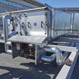 MDM Damian Grabiwski - Montaż centrali wentylacyjnej na dachu budynku, widoczne kanały wentylacyjne, pompa obiegowa Grundfos i elementy instalacji hydraulicznej.