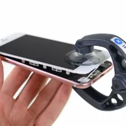 Różowy iPhone otwarty przy użyciu narzędzia z przyssawką iFixit, ukazującego wnętrze urządzenia.