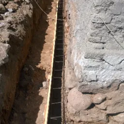 Wykop fundamentowy z drewnianym szalunkiem i zbrojeniem stalowym, przygotowany do izolacji w Miłkach, widok z góry.