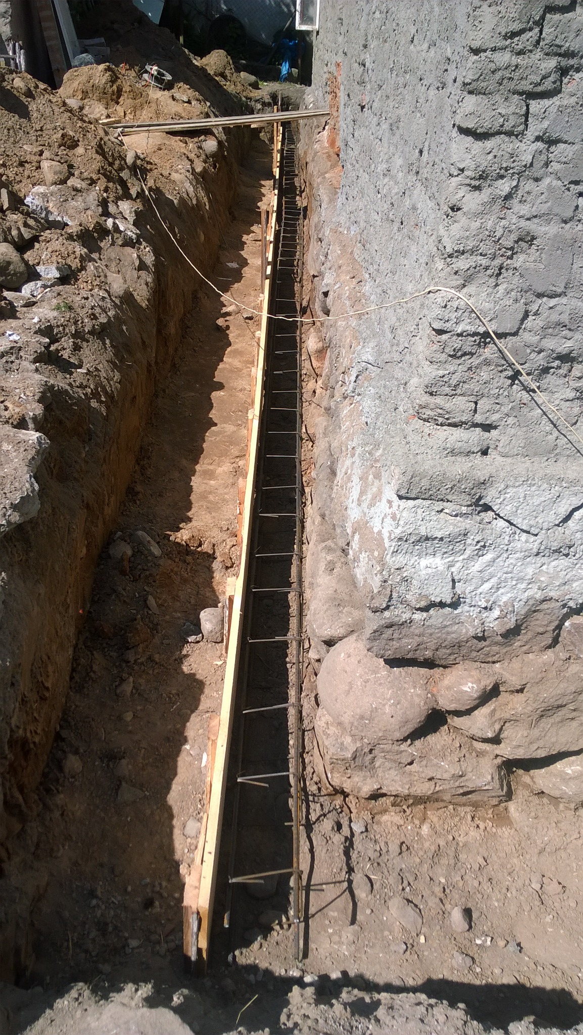 Wykop fundamentowy z drewnianym szalunkiem i zbrojeniem stalowym, przygotowany do izolacji w Miłkach, widok z góry.