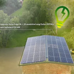 Panele słoneczne Longi Solar 350 Wp, zamontowane na dachu budynku z cegły, z widocznym inwerterem Solar Edge 9k i mocą instalacji 9,8 kW, otoczone zielenią drzew i trawników.