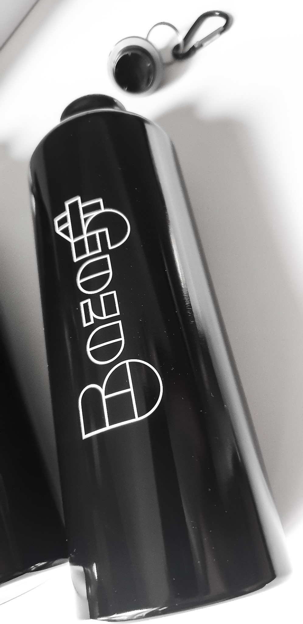 Czarna, metalowa butelka z białym, nowoczesnym nadrukiem logo na białym tle.