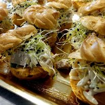 Elegancko podane ptysie z farszem i dekoracją z kiełków na złotej tacy.