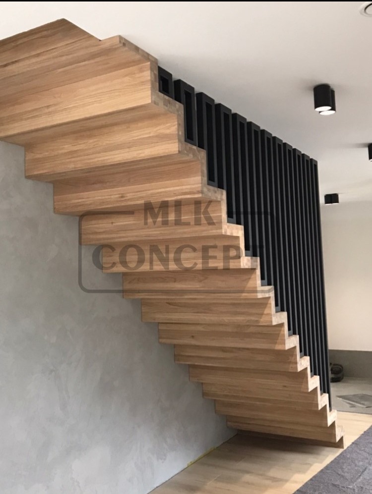 Nowoczesne schody z jasnego drewna z czarną balustradą w formie pionowych listew, oświetlone punktowymi lampami sufitowymi, widoczne z boku na tle szarej ściany.