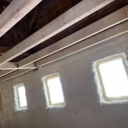 Poddasze w Bardo po ociepleniu pianą poliuretanową, widoczne drewniane belki stropowe i zabezpieczone okna dachowe.