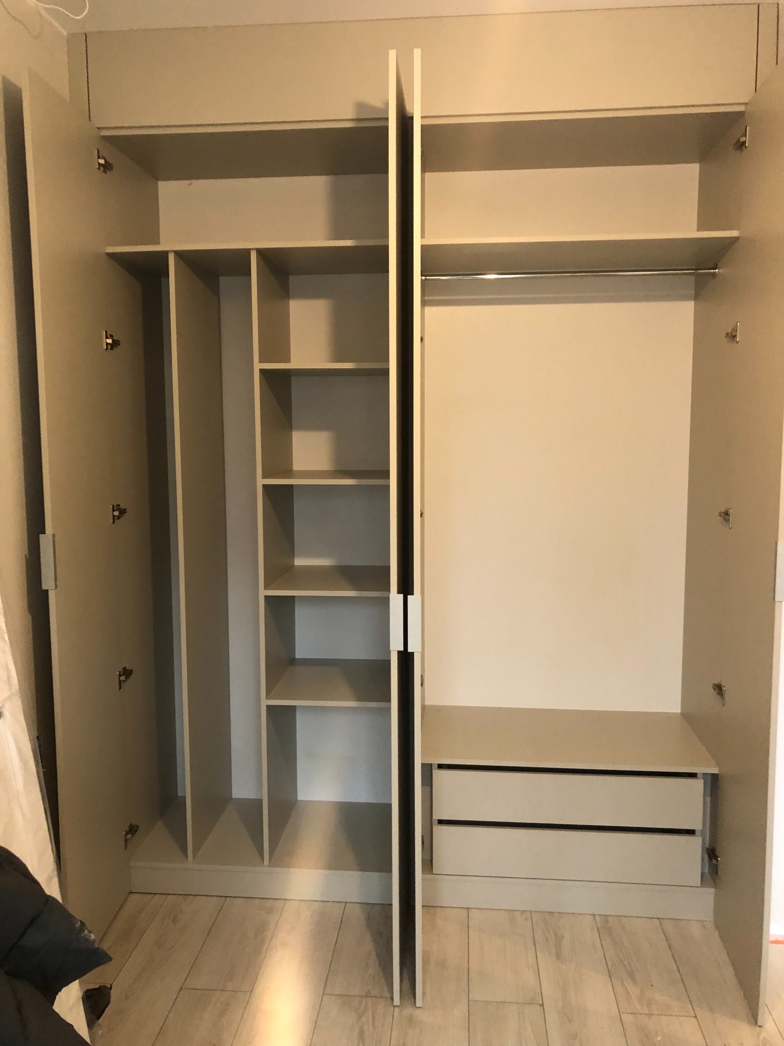 Otwarta szafa z jasnego drewna z półkami po lewej stronie i dwiema szufladami po prawej, widok na wnętrze z perspektywy użytkownika.