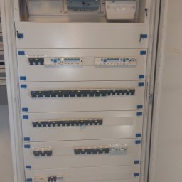 B.R.T- BP Sp. z o.o. - Otwarta szafa elektryczna z licznikami i zabezpieczeniami różnicowoprądowymi, widoczne bezpieczniki sekcyjne i wyłącznik główny, elementy opisane etykietami.