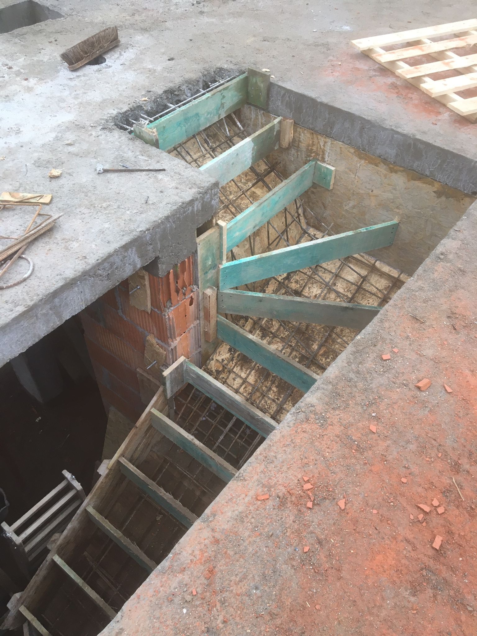 Wykop ze szalunkiem i zbrojeniem pod betonowe schody wewnętrzne na placu budowy, widok z góry.