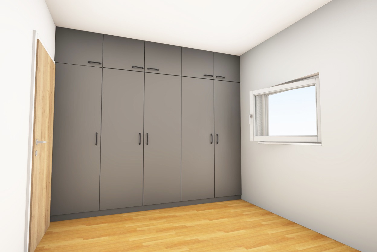 Szara zabudowa szafowa z górnymi szafkami i podłużnymi uchwytami, widoczna obok drewnianych drzwi i okna w białej ramie na jasnej ścianie.