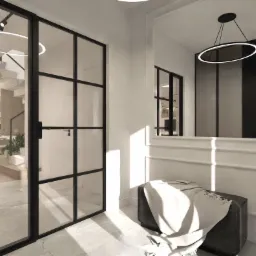 Eleganckie wnętrze: czarne, szklane drzwi z widokiem na schody, pufa z narzutą i dekoracyjne lustro z designerską lampą. Stonowana kolorystyka.