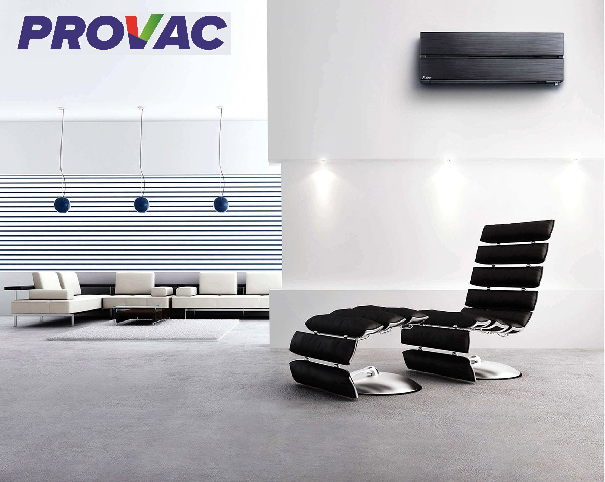 Nowoczesny salon z czarną klimatyzacją ścienną Mitsubishi, designerskim fotelem i sofą w tle, oświetlony trzema wiszącymi lampami.