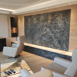 EL-TOM Karol Tomczyk - Salon z nowoczesnym oświetleniem punktowym, kamienną ścianą akcentującą i beżowymi fotelami obrotowymi.