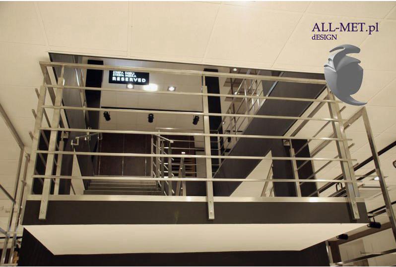 Wnętrze budynku z widoczną klatką schodową zabezpieczoną balustradą ze stali nierdzewnej, widok z dołu na górę, w tle tablica informacyjna 'Reserved'.
