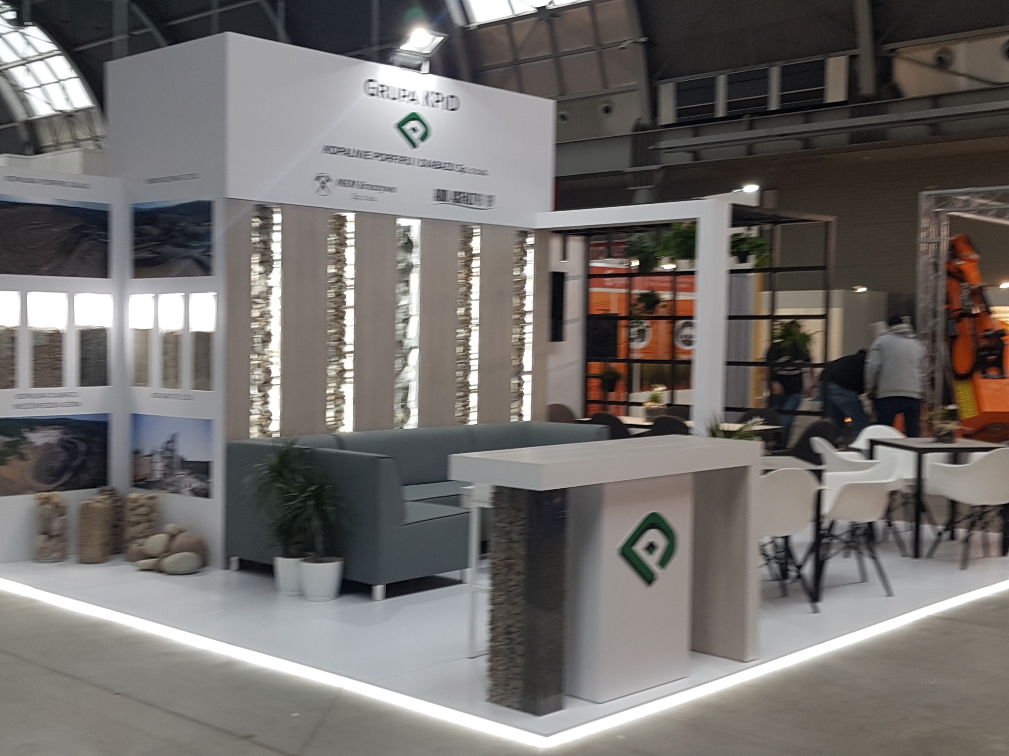 Aranżacja stoiska targowego firmy Grupa KPD z szarą sofą, kolumnami z kamienia dekoracyjnego i elementami identyfikacji wizualnej.