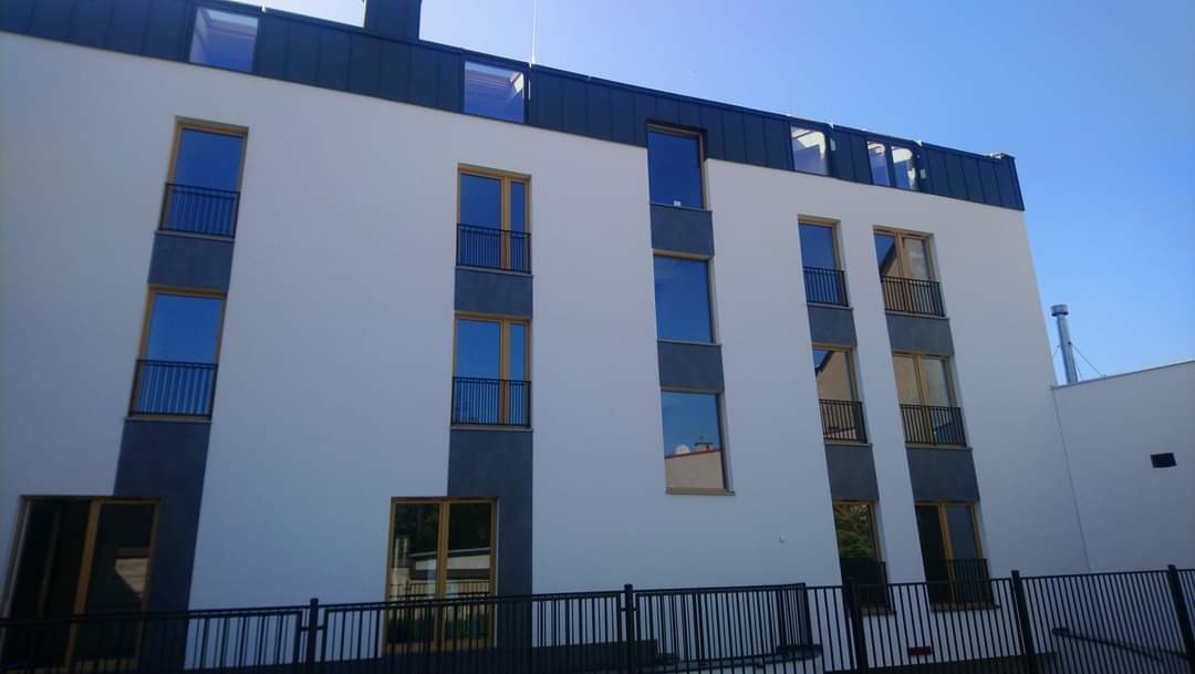 Elewacja budynku mieszkalno-usługowego z balkonami z metalowymi balustradami, widok z dołu w słoneczny dzień, Kraków, aleja 29 listopada.