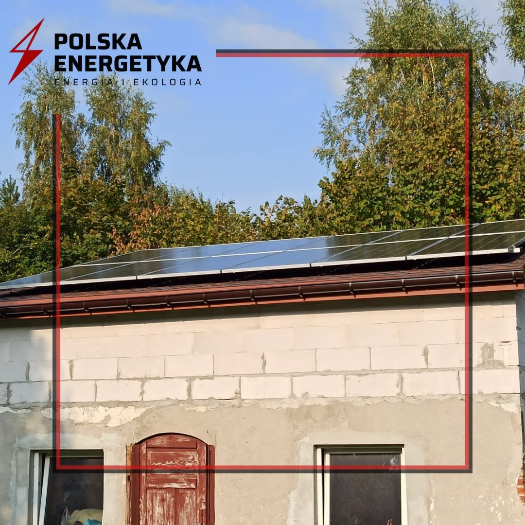 Panele słoneczne na dachu budynku gospodarczego z pustaków, widoczne logo firmy Polska Energetyka.