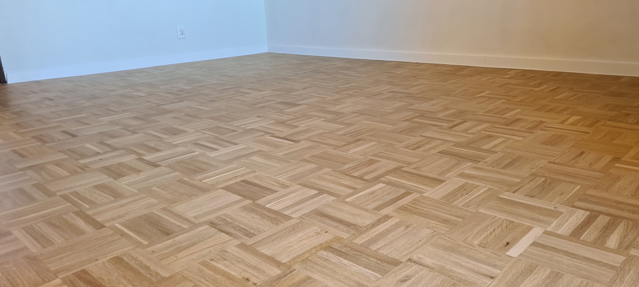 Ułożony parkiet w jodełkę francuską, widok z niskiego kąta, świeżo po cyklinowaniu we Wschowie, z widoczną listwą przypodłogową.