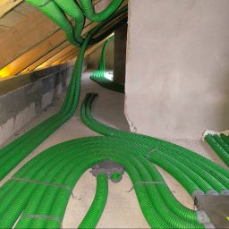 BLOWING - Rozprowadzenie zielonych rur wentylacyjnych w surowym wnętrzu poddasza, widoczne elementy montażowe i łączenia.