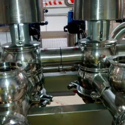 Zestaw precyzyjnych, polerowanych zaworów kulowych ze stali nierdzewnej z elementami mocującymi, tworzących skomplikowany system rurociągów przemysłowych.