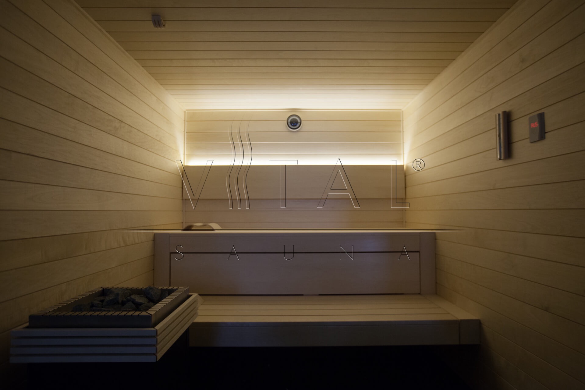 Wnętrze drewnianej kabiny z kamieniami w piecu, oświetleniem LED i panelem sterowania na ścianie, widok z dołu.