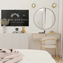 Jasna sypialnia z toaletką, okrągłym lustrem i telewizorem z logo firmy projektującej wnętrza, złoty piesek na komodzie.