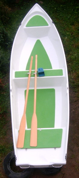 Biała, dwupłaszczowa łódź wiosłowa 4,2m z zielonymi elementami i wiosłami, widok z góry, na tle trawy i opony.