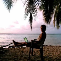 Kobieta siedzi na krześle na plaży z laptopem, palmy w tle, zachód słońca nad oceanem.