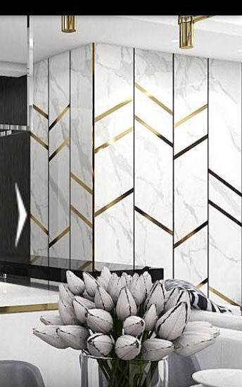 Ściana wykończona panelami z wzorem marmuru i złotymi akcentami, bukiet białych tulipanów w szklanym wazonie na pierwszym planie.