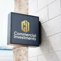Kwadratowy szyld z logo i nazwą firmy 'Commercial Investments' zamocowany na szarej ścianie z płytek.