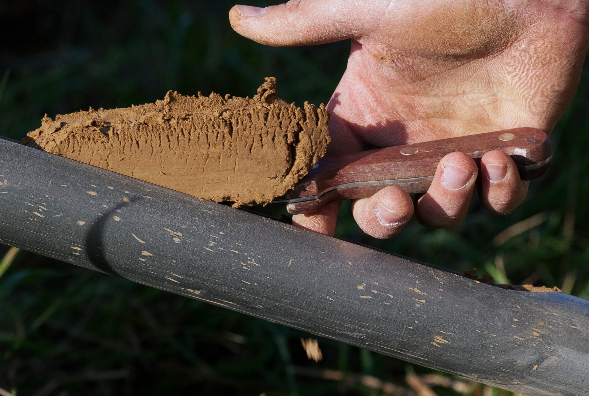 Pobieranie próbki gleby nożem z rury rdzeniowej. Analiza gruntu na budowie, badania geologiczne pod inwestycje. Przekrój warstw ziemi.