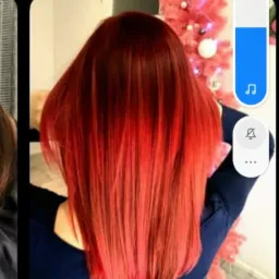 Intensywnie czerwone włosy z gradientem, widoczne od tyłu, z delikatnym połyskiem, na tle rozmytej choinki.