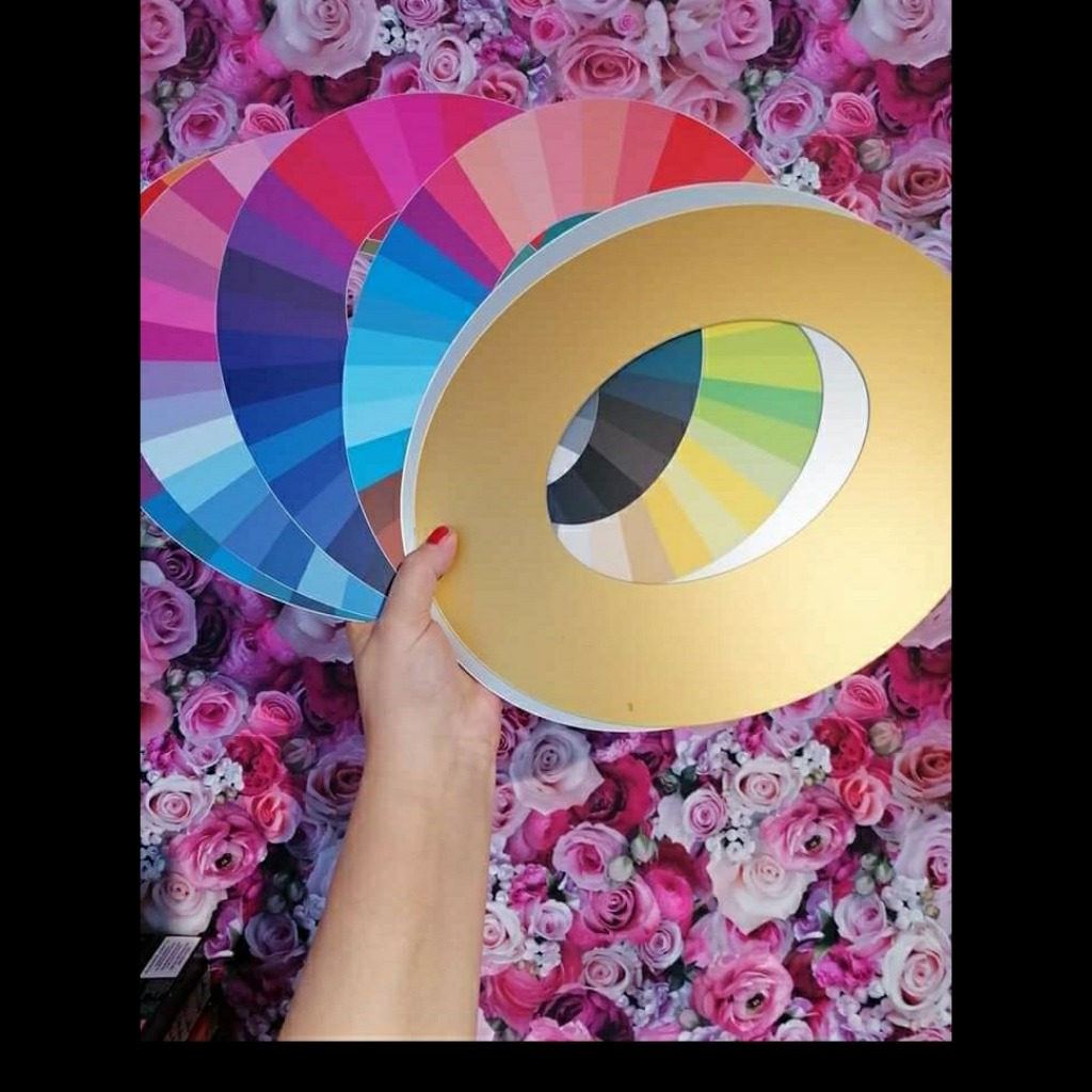 Paleta kolorów z okrągłym złotym szablonem na tle ściany z różami.